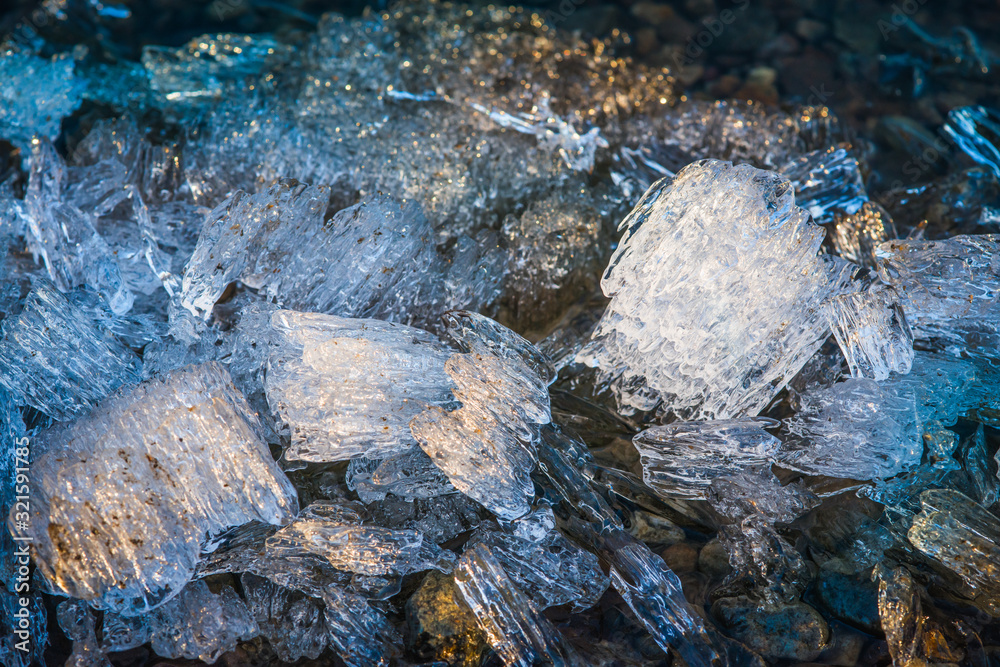 Pieces of melting ice under the bright Spring sun on the river bank. Selective focus macro shot with shallow DOF Pieces of melting ice under the bright Spring sun on the river bank. Selective focus macro shot with shallow DOF