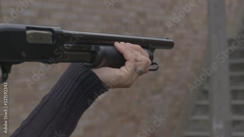 Side view of a person aiming a pump action shotgun with a folding stock photo