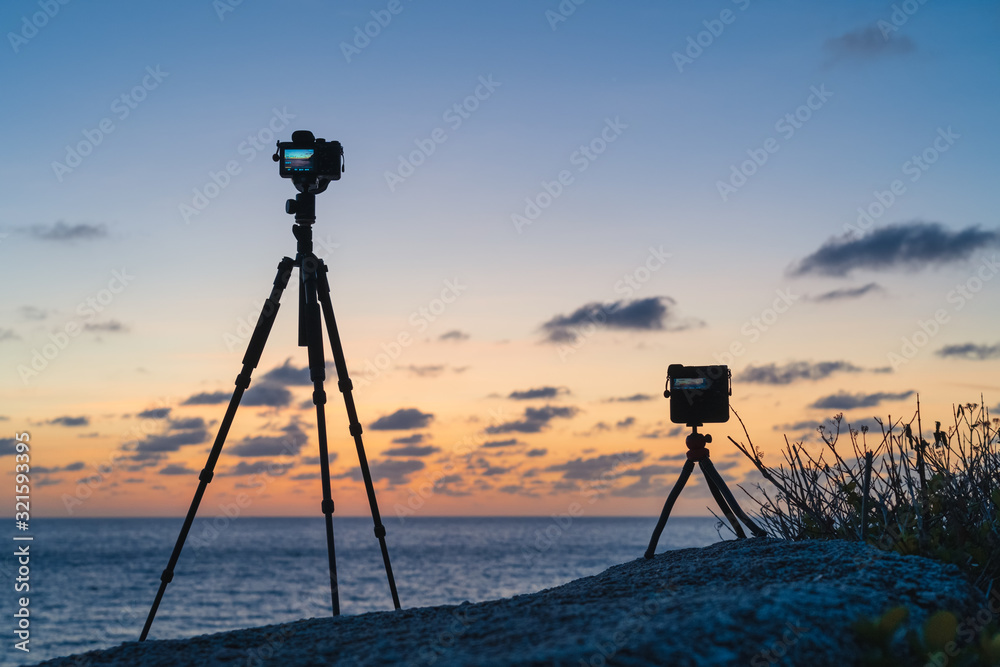 Two cameras standing on a tripods on the beach against the background of dawn Two cameras standing on a tripods on the beach against the background of dawn