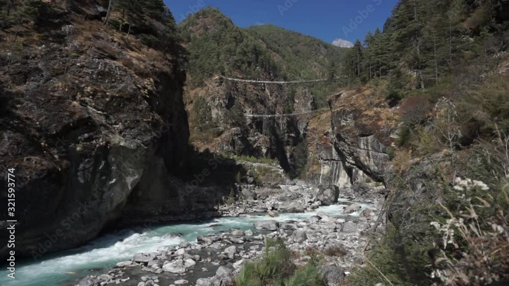 The river in a high rocky valley beside a suspension bridge above. The river in a high rocky valley beside a suspension bridge above.