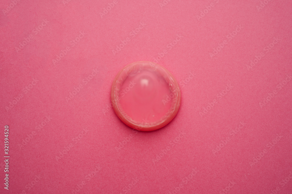 Condom week and valentines day concept with pink condom and heart shape beads and sperm cut out. Men protection erection latex wrapped Condom week and valentines day concept with pink condom and heart shape beads and sperm cut out. Men protection erection latex wrapped