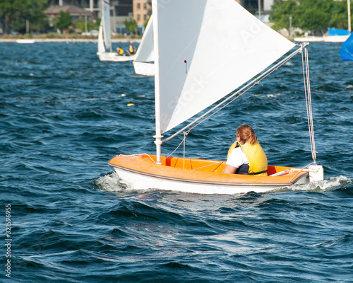 Sole female sailor Sailing small sailboat solo on an inland waterway.