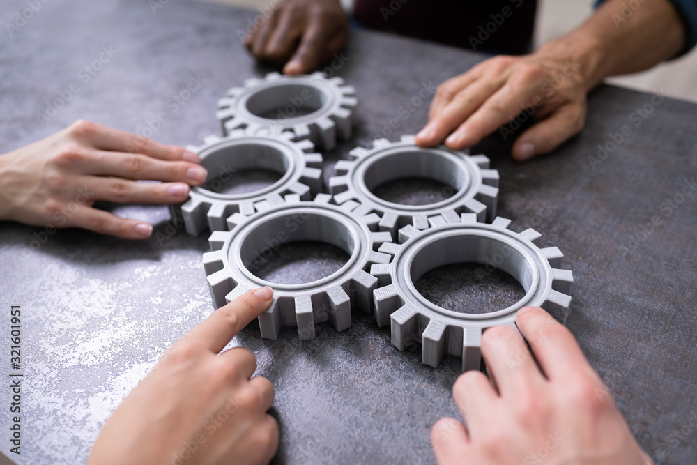 Businesspeople Joining Gears On Desk