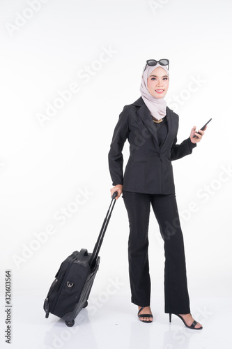 Muslim businesswoman in a hijab on a business trip with luggage isolated on white background. Suitable for cut out  manipulation or composite works for travel or business concept. Full length portrait
