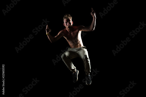 Silhouette of dancer in jump with rising hands