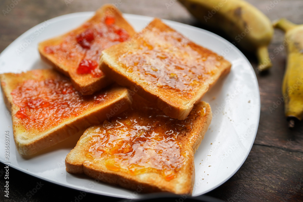 Plate with slices of bread and delicious strawberry jam on wooden table