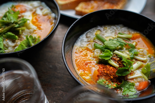 Congee with minced pork and slices of bread and delicious strawberry jam is a favorite breakfast for Thai people. on wood table texture.