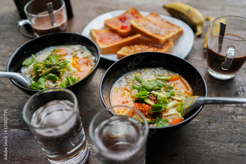 Thai congee with minced pork and egg is a favorite breakfast for Thai people. on wood table texture.