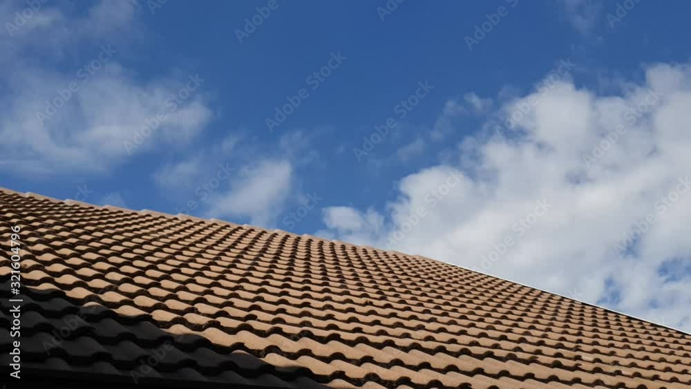 Beautiful blue summer sky with dense thick rain clouds moving across the horizon over a tiled roof cloudscape time lapse Beautiful blue summer sky with dense thick rain clouds moving across the horizon over a tiled roof cloudscape time lapse