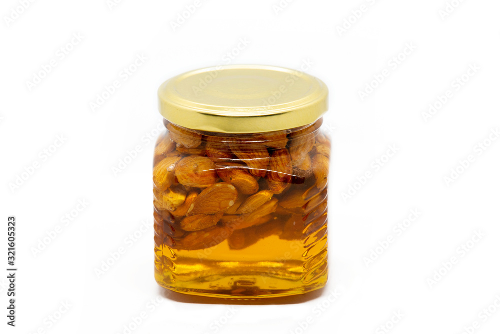 Glass jar with honey and almonds on white background