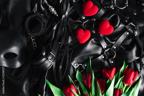 on Valentine's day, a set of adult toys on a black silk background. red Tulip