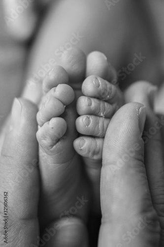 Newborn Baby's feet. Mother and father holding newborn baby legs,legs massage concept of childhood, health care, IVF, hygiene