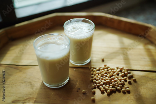 Soy milk homemade in glass cup decorated by soybean on wooden table background.
