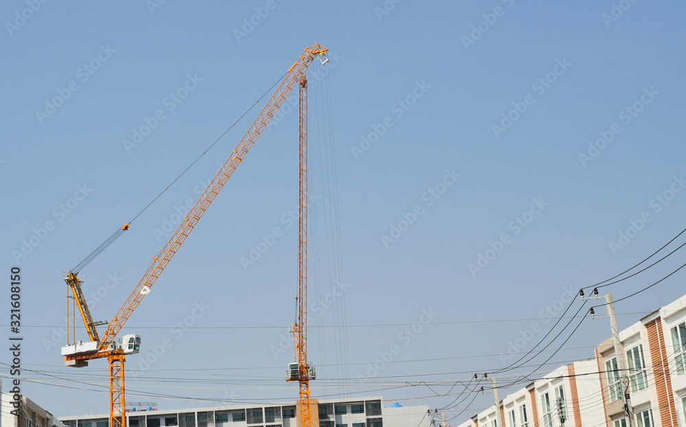 Yellow tower crane in the building construction area with blue sky in background, Machinery and large working equipment