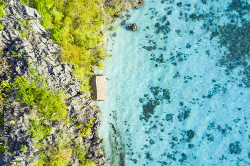 View from above, stunning aerial view of a bungalow surrounded by rocky cliffs bathed by a turquoise, crystal clear sea. Malwawey Coral Garden, Coron Island, Palawan, Philippines. © Travel Wild