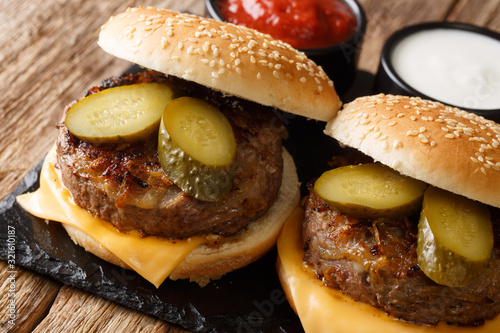 American flavored Oklahoma fried onion burgers with cheddar cheese and pickles close-up on a slate board. horizontal