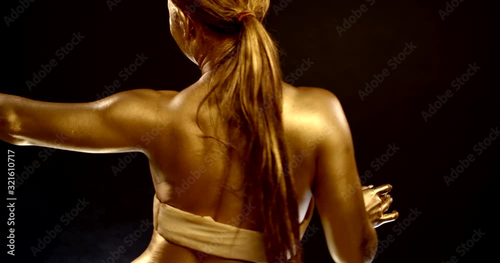 graceful woman is covered golden paint is dancing, wriggling her body and hands graceful woman is covered golden paint is dancing, wriggling her body and hands