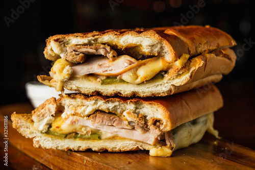 Traditional cuban sandwich with cheese, ham and fried pork, served on a wooden board photo
