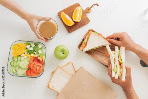 Young couple having breakfast with sandwiches at table in kitchen, closeup