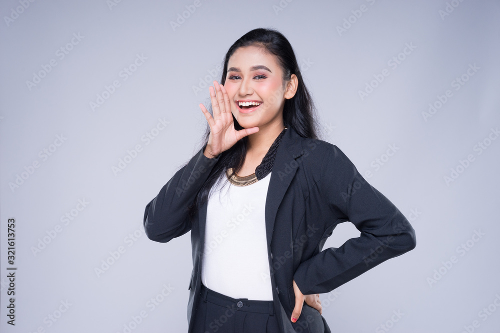 An attractive woman wearing business attire with gestures towards copyspace area isolated on grey. Good for manipulation works for technology, transportation, business or finance theme. An attractive woman wearing business attire with gestures towards copyspace area isolated on grey. Good for manipulation works for technology, transportation, business or finance theme.