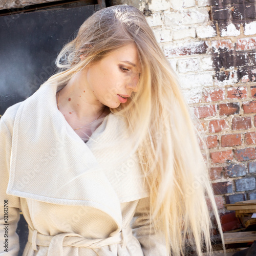 Obraz na płótnie Street portrait of blonde with long hair, in a light beige raincoat w salonie