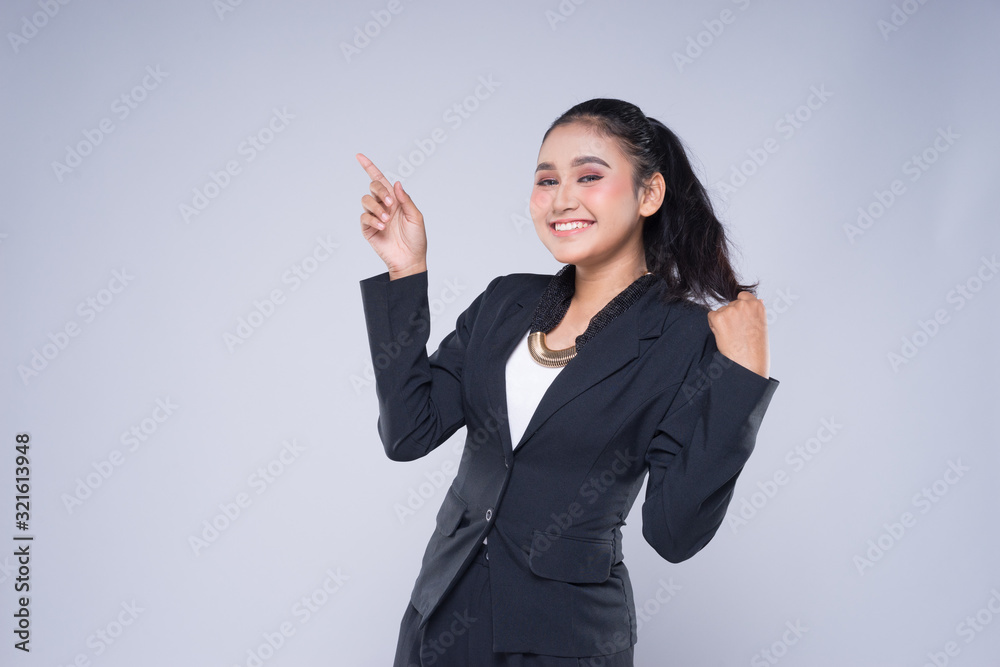 An attractive woman wearing business attire with gestures towards copyspace area isolated on grey. Good for manipulation works for technology, transportation, business or finance theme. An attractive woman wearing business attire with gestures towards copyspace area isolated on grey. Good for manipulation works for technology, transportation, business or finance theme.