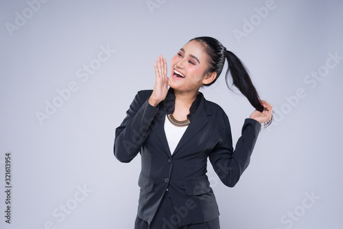 An attractive woman wearing business attire with gestures towards copyspace area isolated on grey. Good for manipulation works for technology, transportation, business or finance theme.