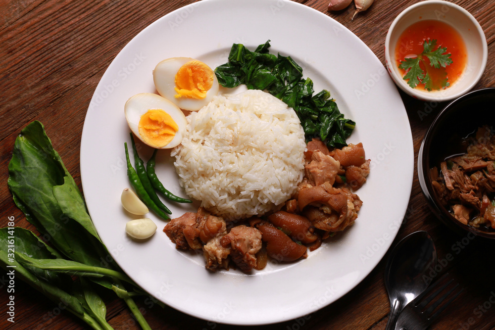 Stewed pork leg on rice on wooden table.Thai food