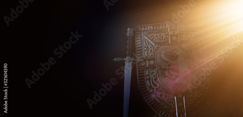 photo of shield knight armor and sword over dark background. Medieval period concept