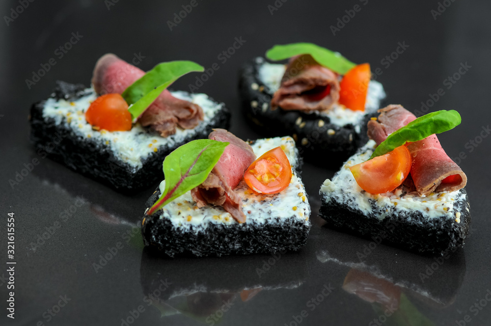 bruschettas on a black bun with meat from the chef on a black background bruschettas on a black bun with meat from the chef on a black background