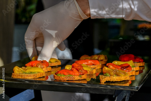 the waiter lays out on a catering canapes with baked sweet pepper 