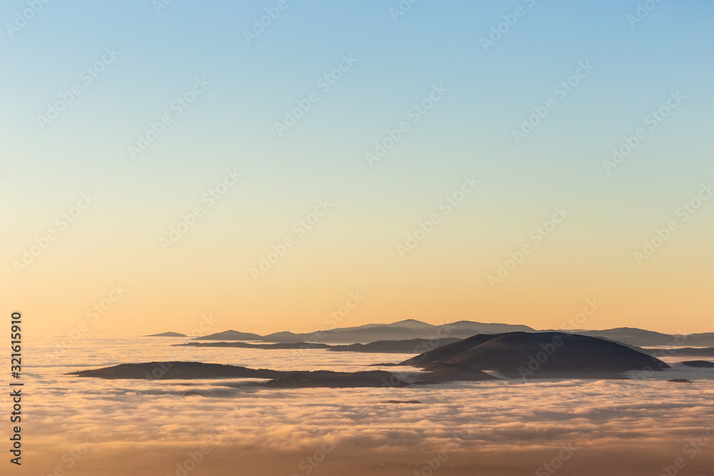 Sea of fog and mist between mountains and hills at dusk
