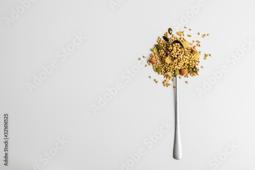 Granola with green buckwheat, nuts and coconut on a spoon on a white background. Healthy food concept. Food for breakfast and snack.