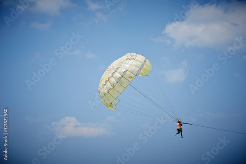 Woman enjoying parasailing, sky background 