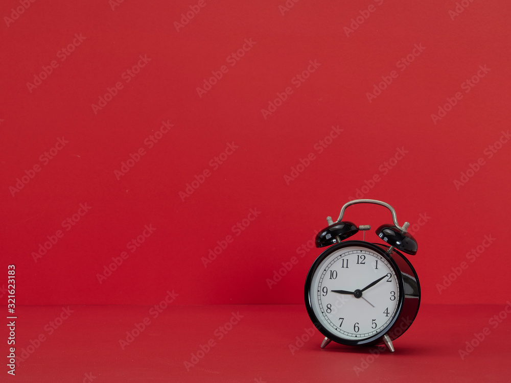 Black alarm clock on red background
