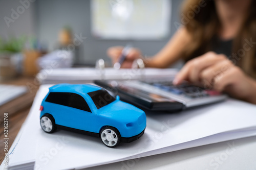 Blue Car In Front Of Businesswoman Calculating Loan