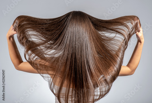 Back view of a brunette woman with a long straight hair.