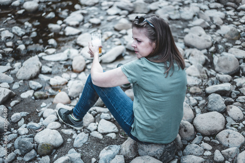 Woman with a glass of beer sitting on rocks