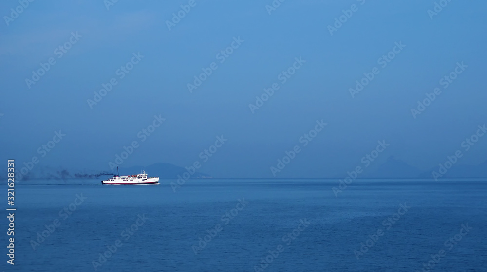 Lonely white ship in the blue sea and blue sky.
