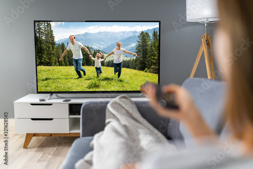 Woman Watching TV While Relaxing On Sofa