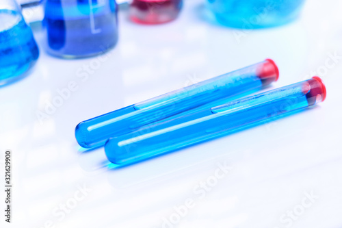 Vials of chemical blue liquid on a white laboratory table.