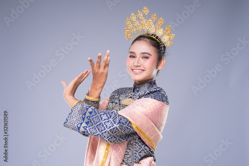 A beautiful Malaysian traditional female dancer with a charming smile performing a cultural dance steps in a traditional outfit. Half length isolated in grey. photo