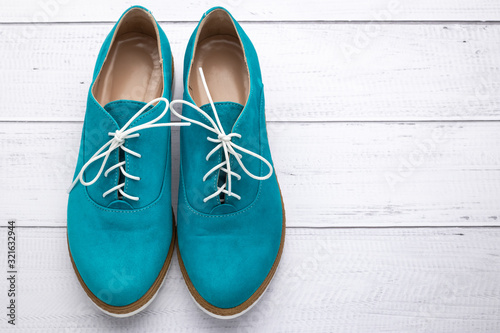 Turquoise lace-up women shoes, suede boots of aqua color. Pair of footwear on white wood background. Copy, text space. Top view. Casual fashion style concept.
