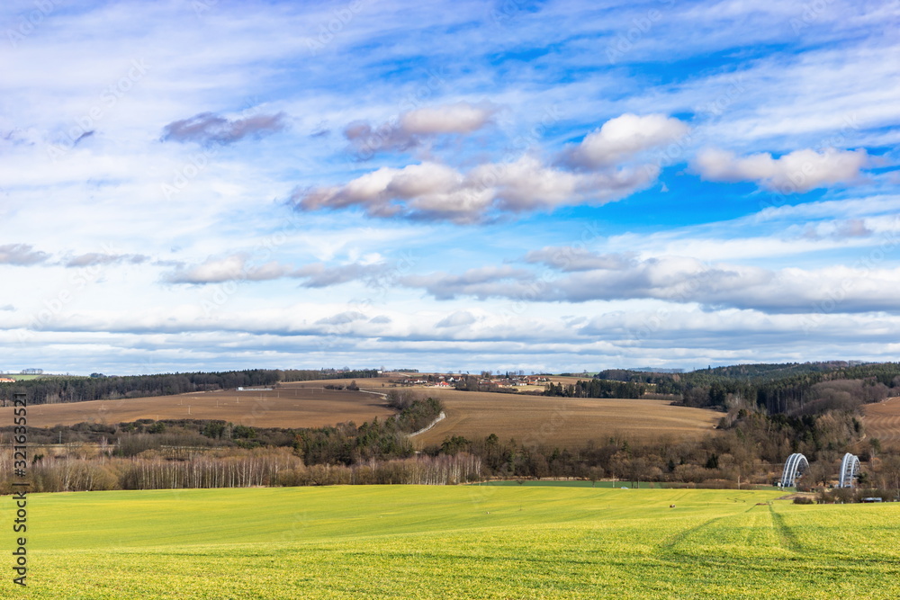 Early spring landscape in South Bohemia. Green field and forest. Blue sky.