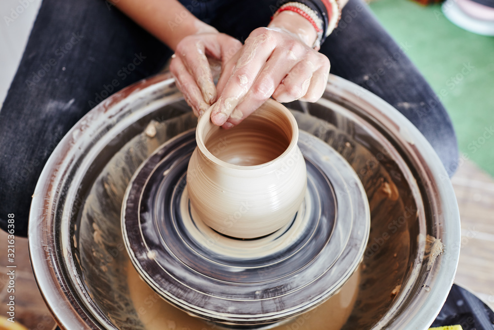 Fototapeta premium Woman's hands molding clay. Potter making ceramic pot in pottery workshop
