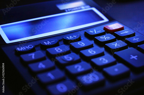 Accounting fraud. Black bookkeeping. Modern office calculator on the table on a dark background.