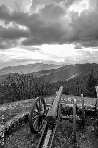 Dramatic autumn black and white view over the mountain range from near Shipka peak, Stara Planina mountain in Central Bulgaria as seen from Shipka Memorial. Moody feeling. Old Russian cannon photo