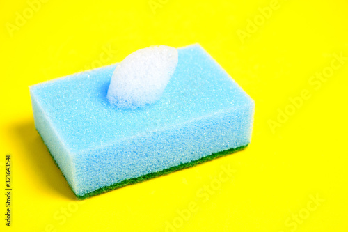 Blue sponge for washing dishes on a yellow background.