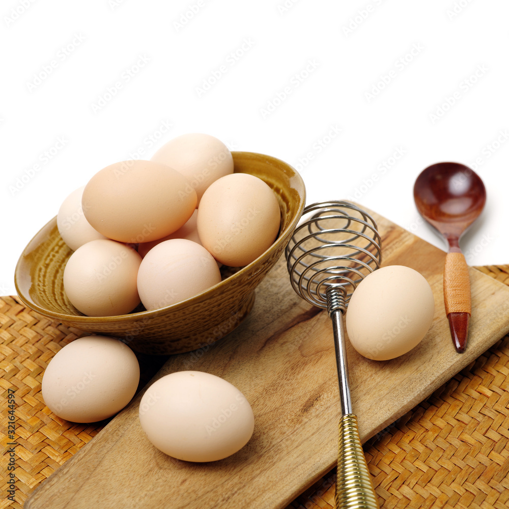 Wire whisk and brown eggs on white background Wire whisk and brown eggs on white background