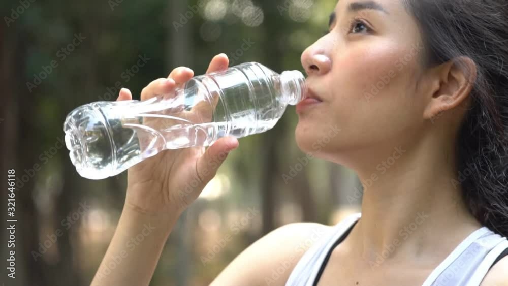 Zoom out slow motion camera panning and focus at young woman drink water from a plastic bottle